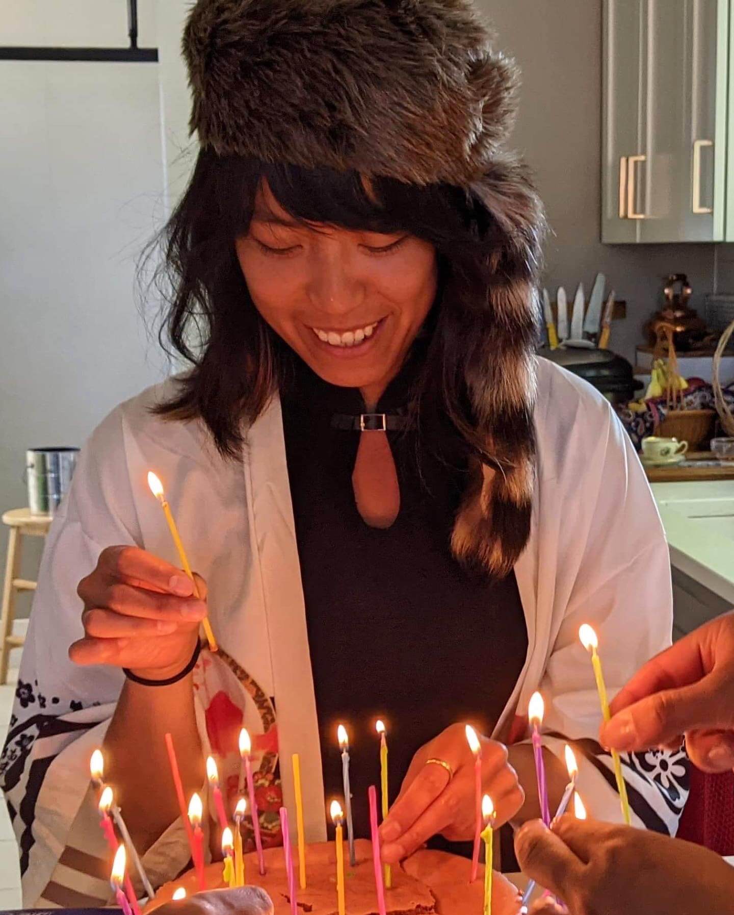 A good birthday Alex in a racoon hat in front of a cake